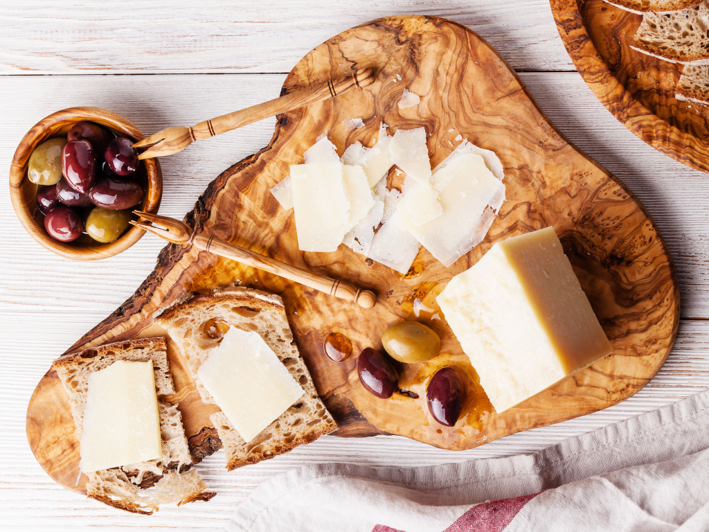 Сыр на доске с хлебом и и оливками