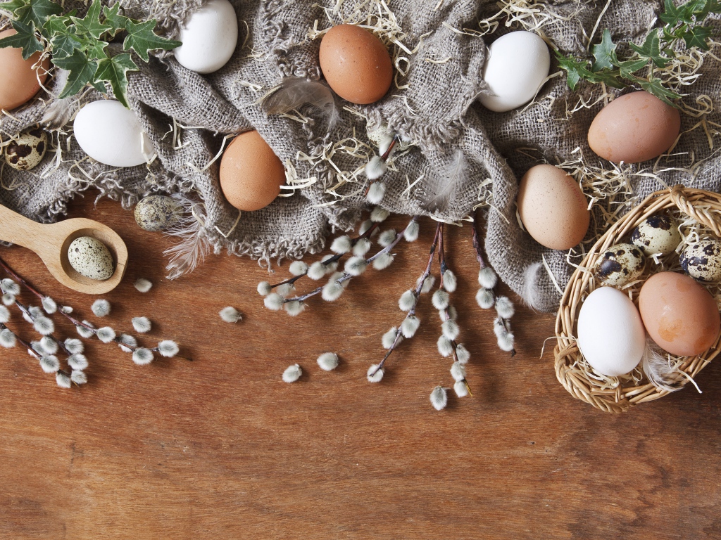 Куриные и перепелиные яйца на столе в ветками вербы
