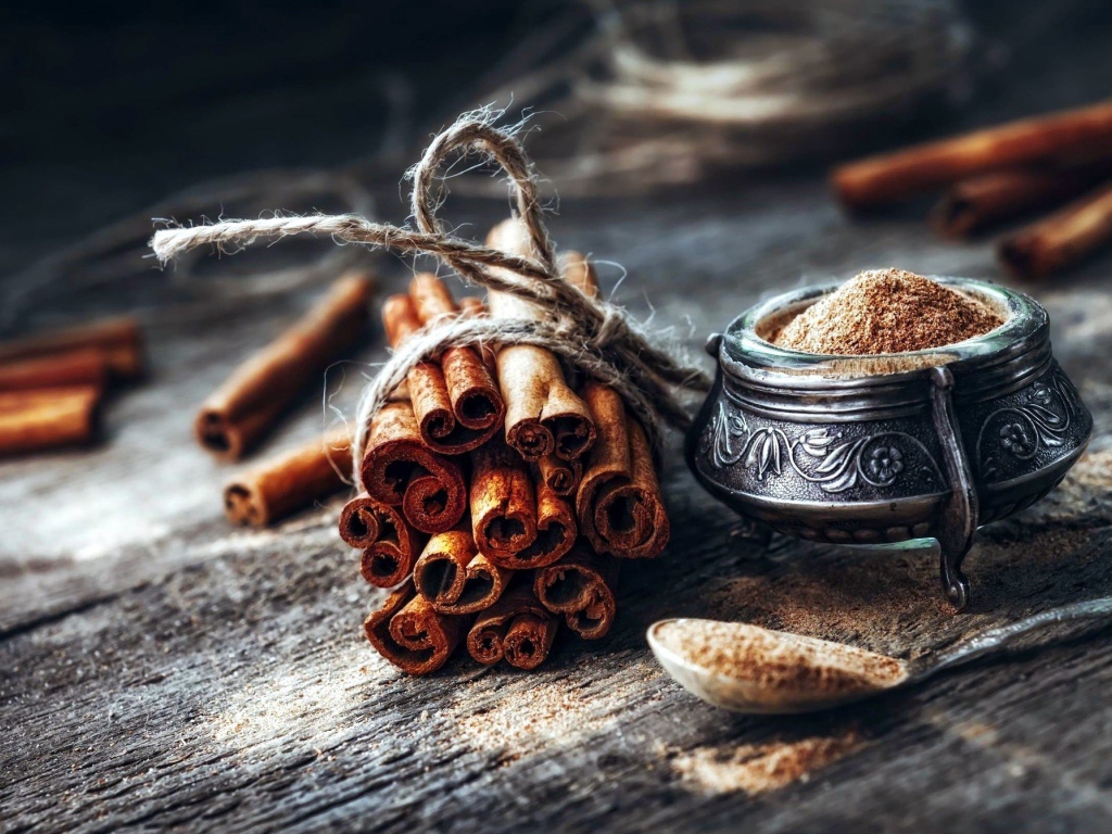 Палочки корицы на столе с молотой корицей
