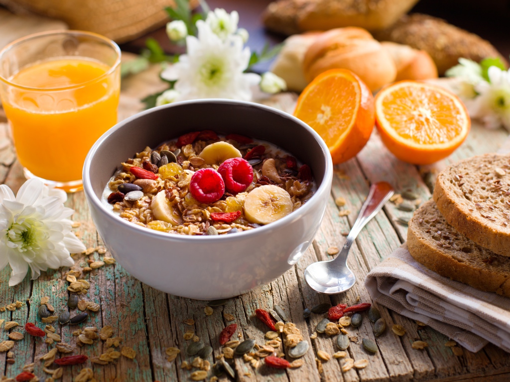 Мюсли в миске с молоком на завтрак с соком и апельсинами 