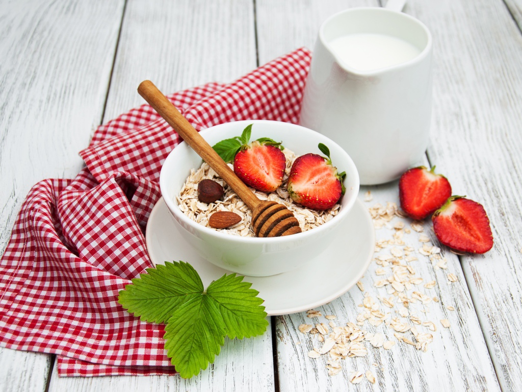 Овсяная каша на столе с молоком и клубникой