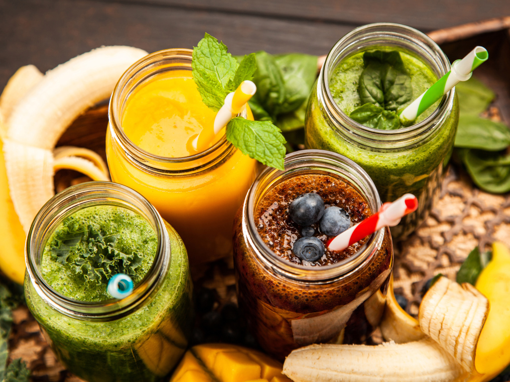 Банки со смузи на столе с бананами