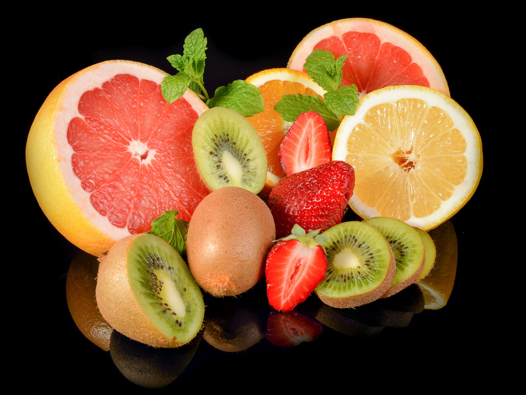 Цитрусовые фрукты на черном фоне с ягодами клубники 