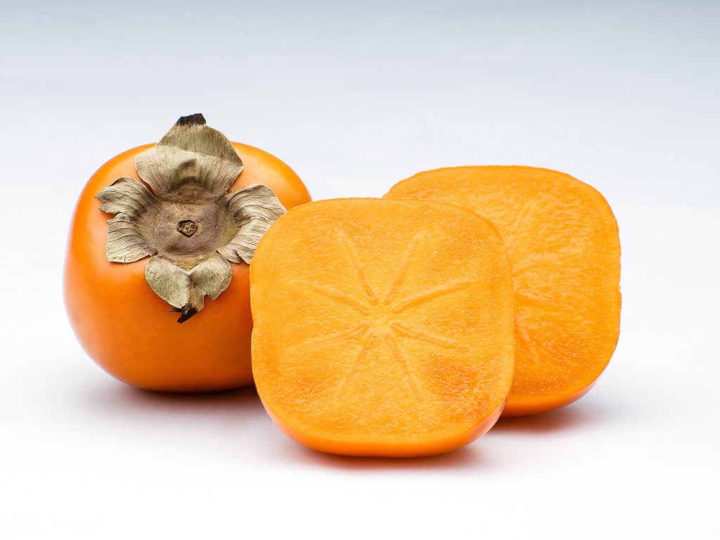 Оранжевая хурма на сером фоне крупным планом