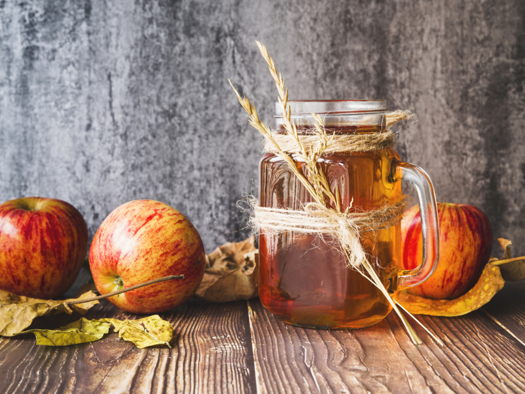 Три яблока с медом на столе на сером фоне