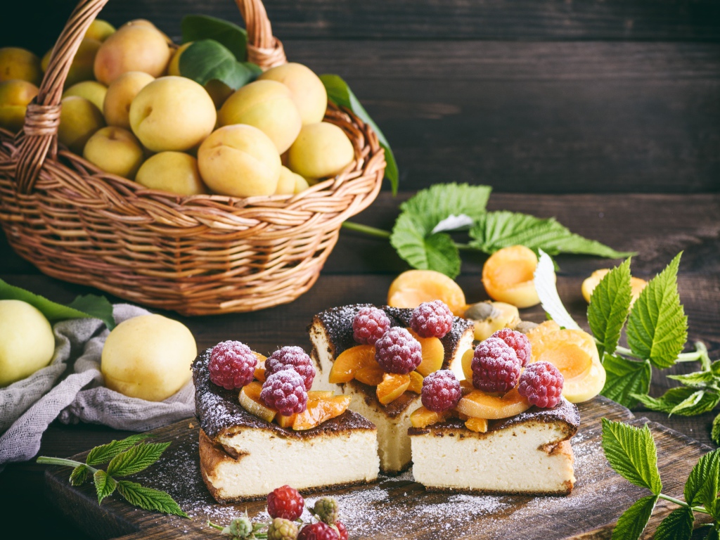 Вкусный фруктово - ягодный пирог на столе с корзиной с абрикосами