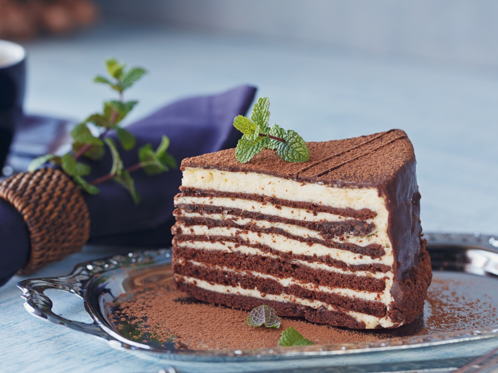 Кусок торта с кремом и какао на блюде 