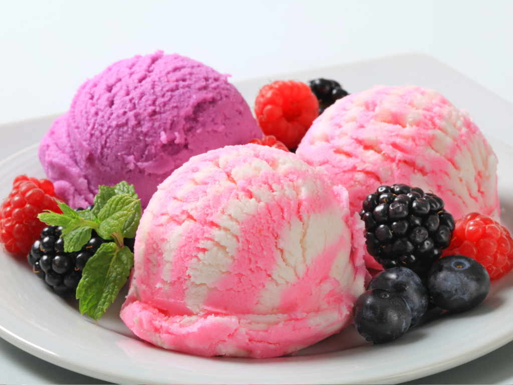 Шарики фруктового мороженого на белой тарелке с ягодами