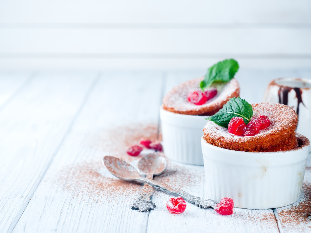 Пирожное с ягодами и сахарной пудрой на столе с ложками