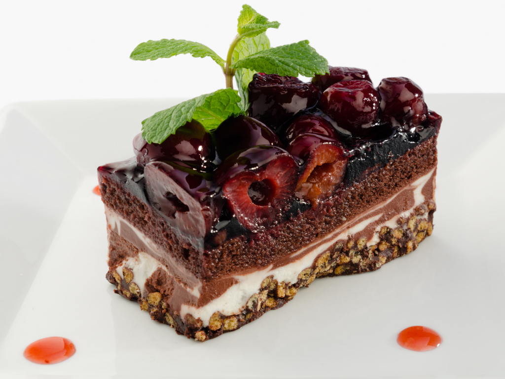 Пирожное с черешней и листиками мяты на сером фоне