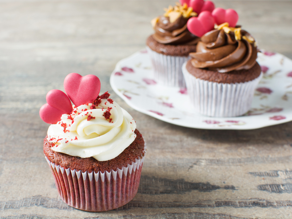 Кекс с кремом и красными сердечками на столе 