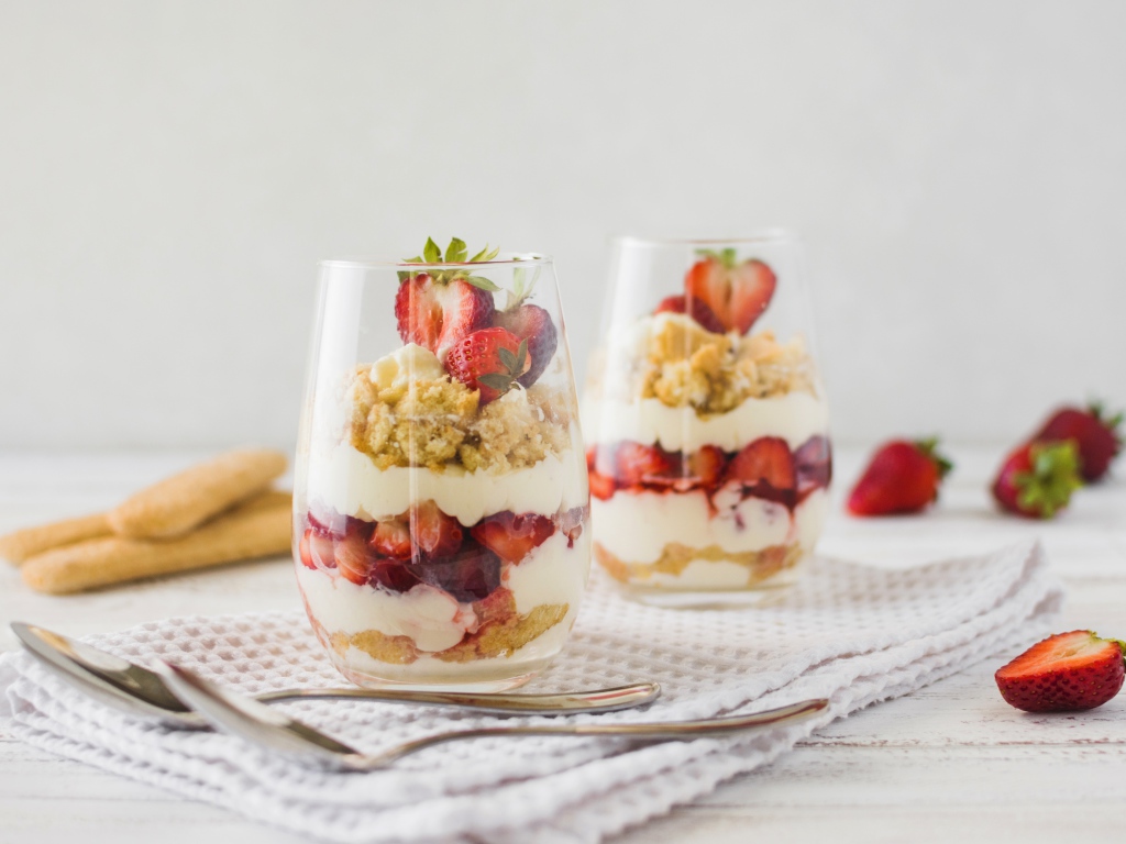 Десерт с клубникой в стеклянных стаканах на столе 