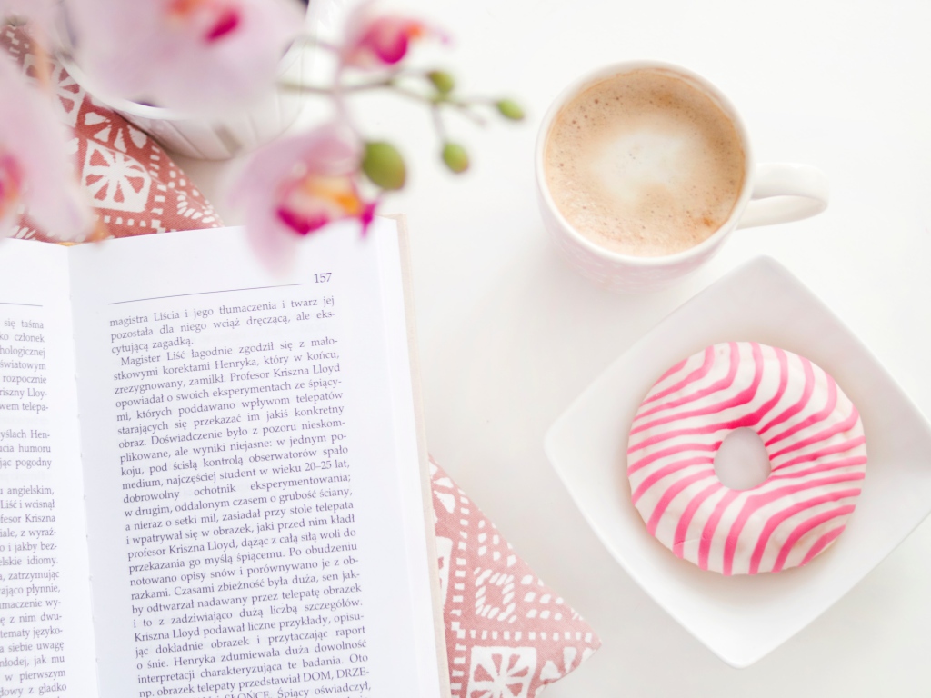 Пончик с чашкой кофе на столе с книгой
