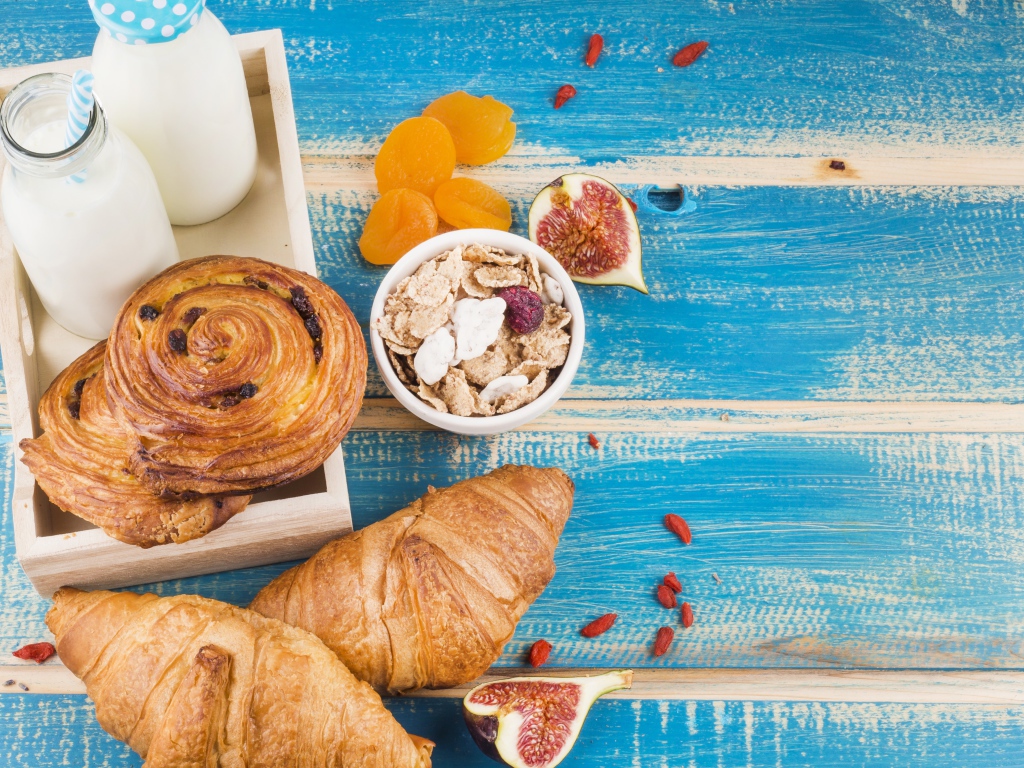 Свежая выпечка, молоко и мюсли на завтрак на столе