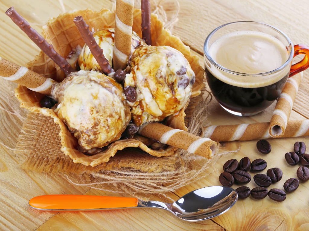 Мороженое с трубочками на столе с кофейными зернами и кофе