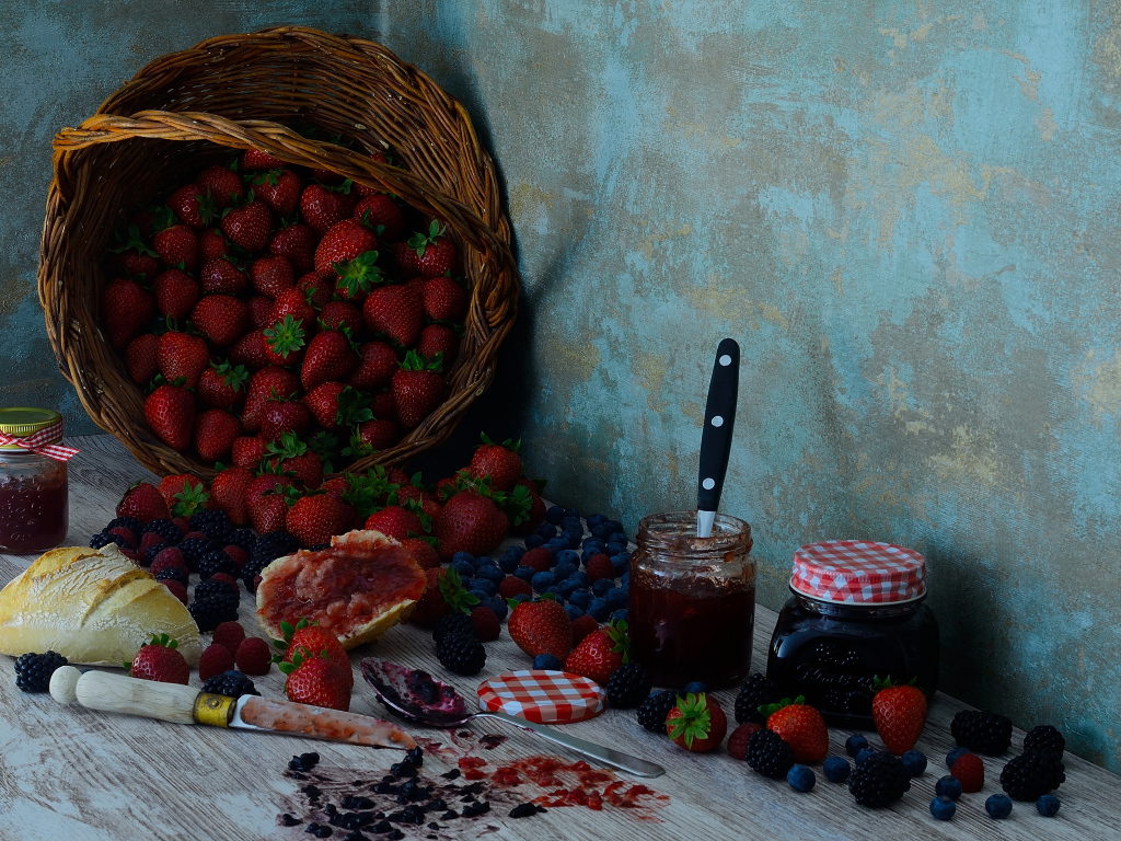 Jam on a table with berries and a loaf