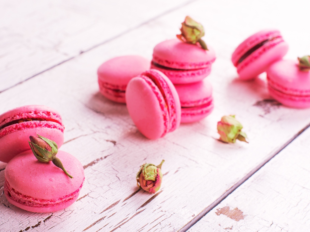 Розовый десерт макарон на столе с сухими розами