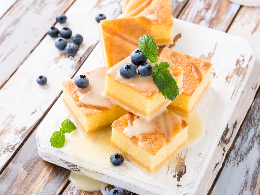 Бисквитные пирожные с сиропом и ягодами черники на столе