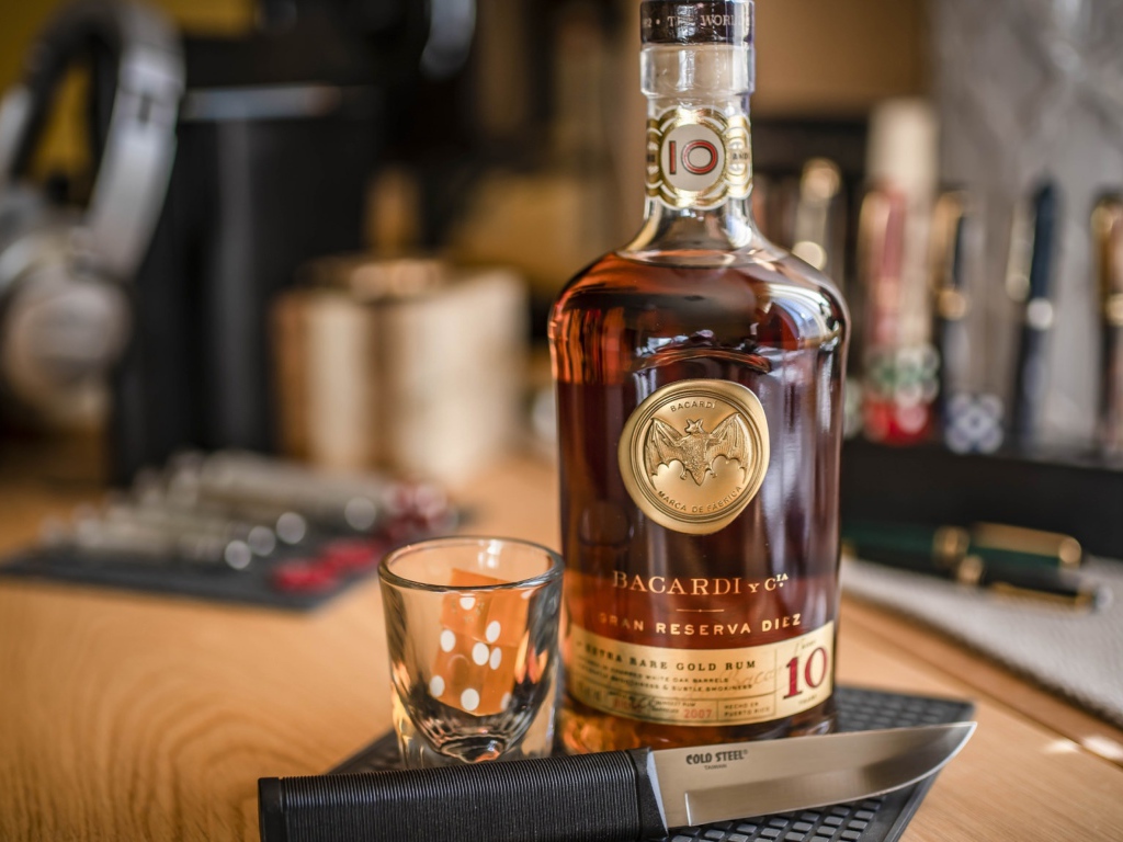 Бутылка виски на столе с рюмкой и ножом