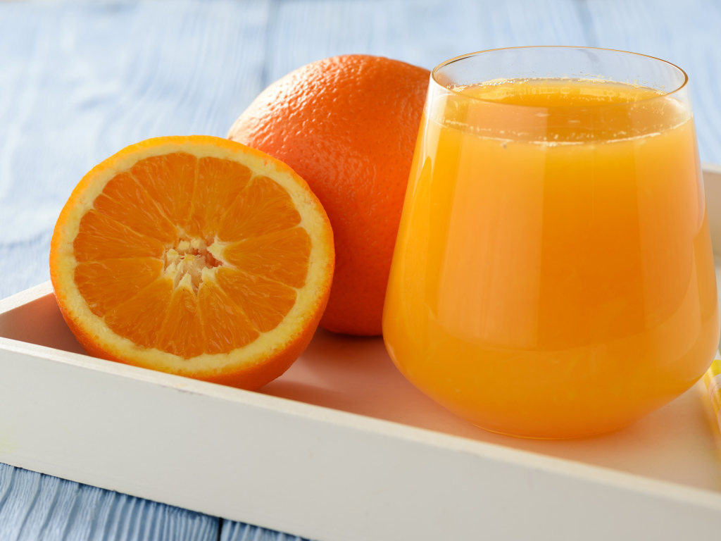Стакан апельсинового сока на столе с апельсином 