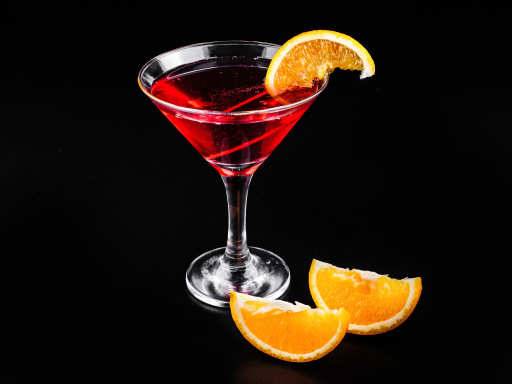 Алкогольный коктейль с кусочками апельсина на черном фоне