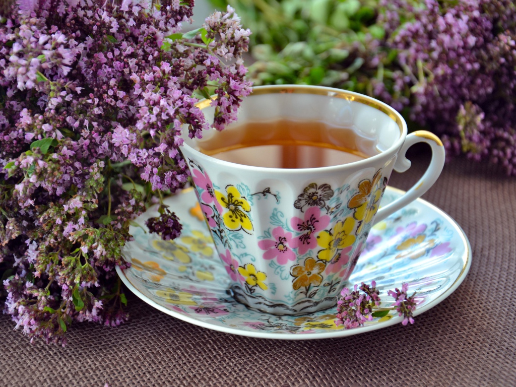 Красивая чашка чаю с цветами мяты на столе