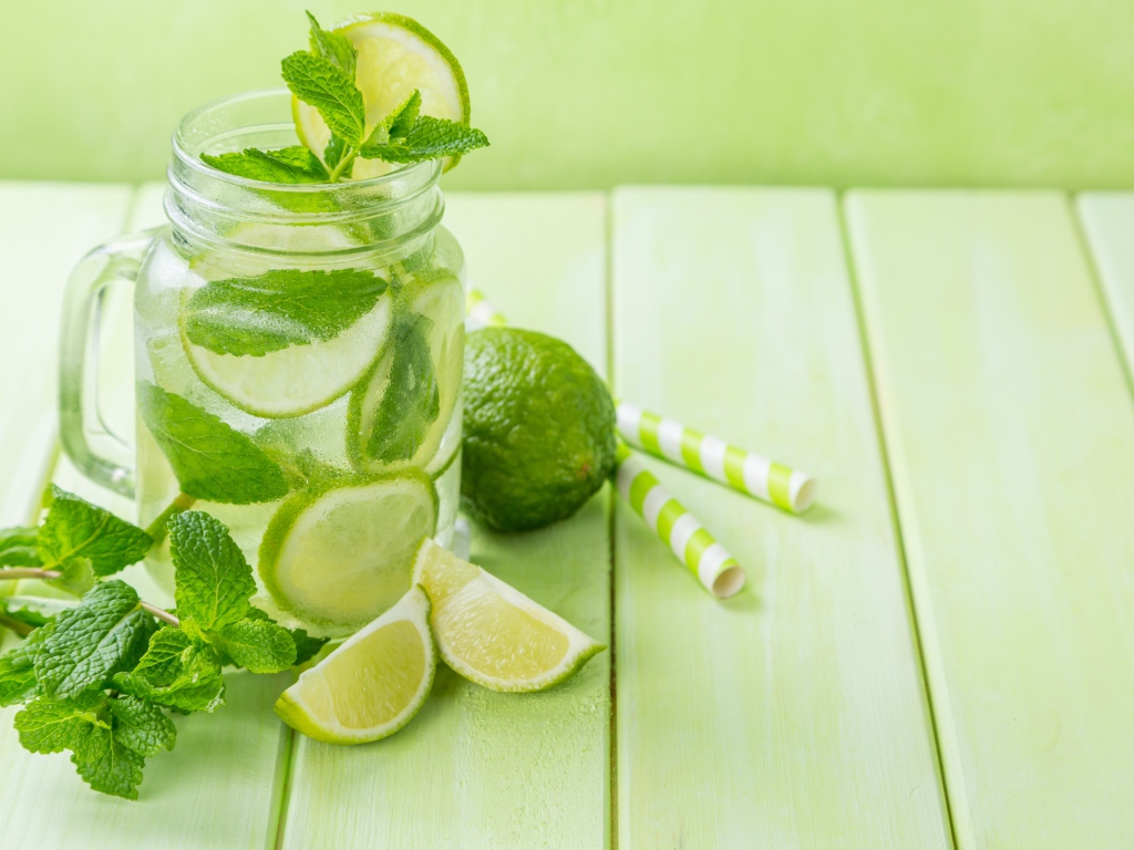 Графин с мохито на столе с лаймом и мятой