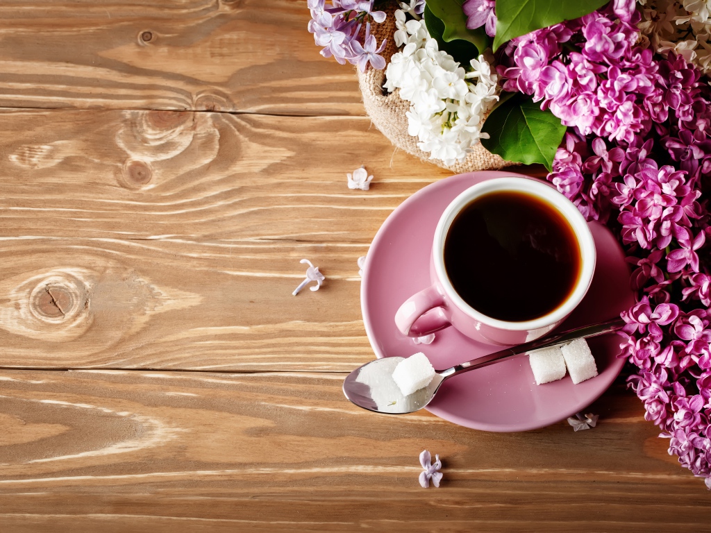Чашка кофе на деревянном столе с сиренью 