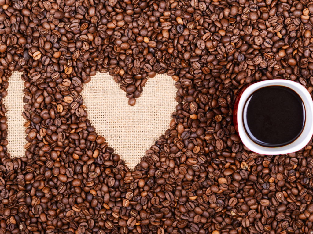 Чашка с кофе стоит на кофейных зернах 
