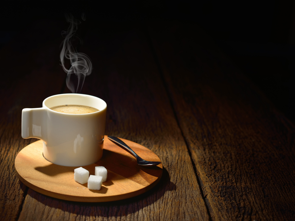 Чашка горячего кофе на столе с сахаром