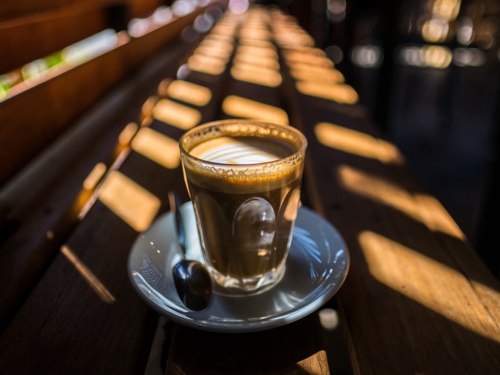 Стакан с кофе стоит на деревянном лавке