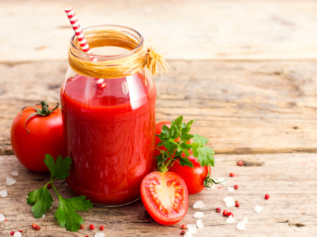 Банка томатного сока на столе с помидорами и петрушкой