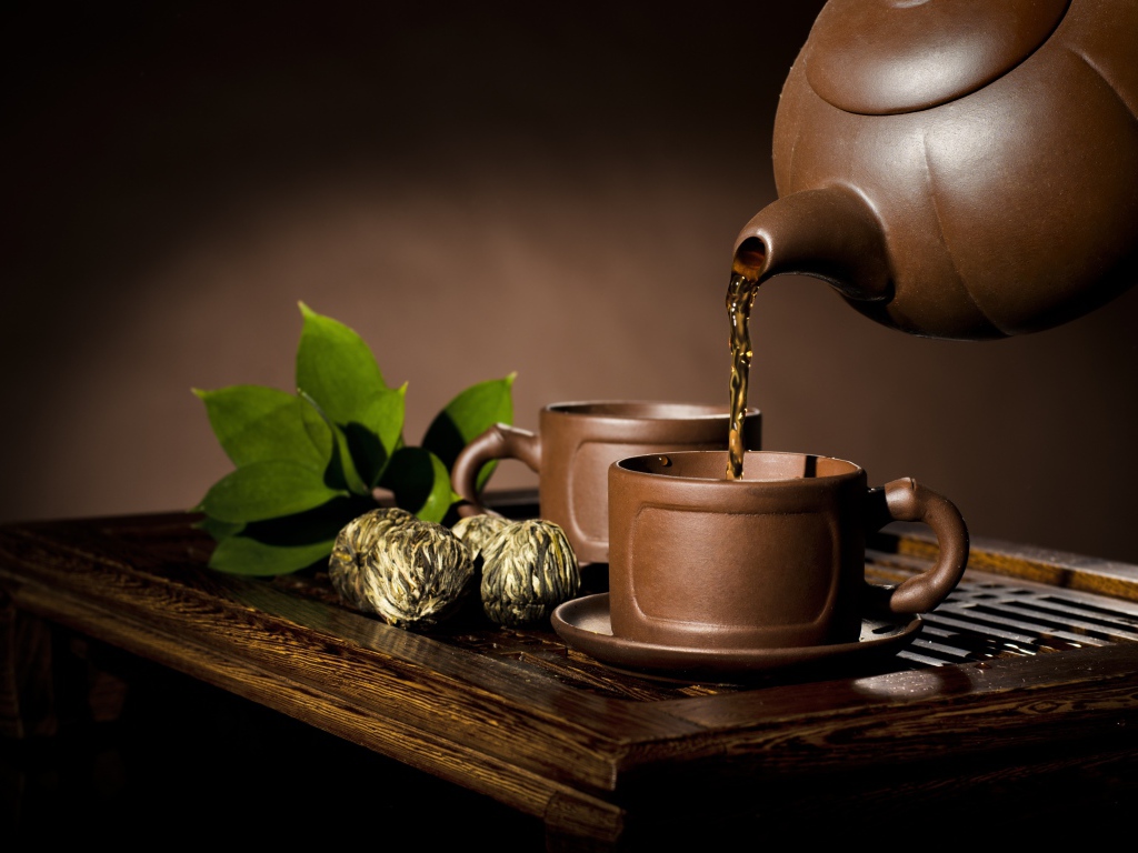 Чай наливают из чайника в коричневую чашку