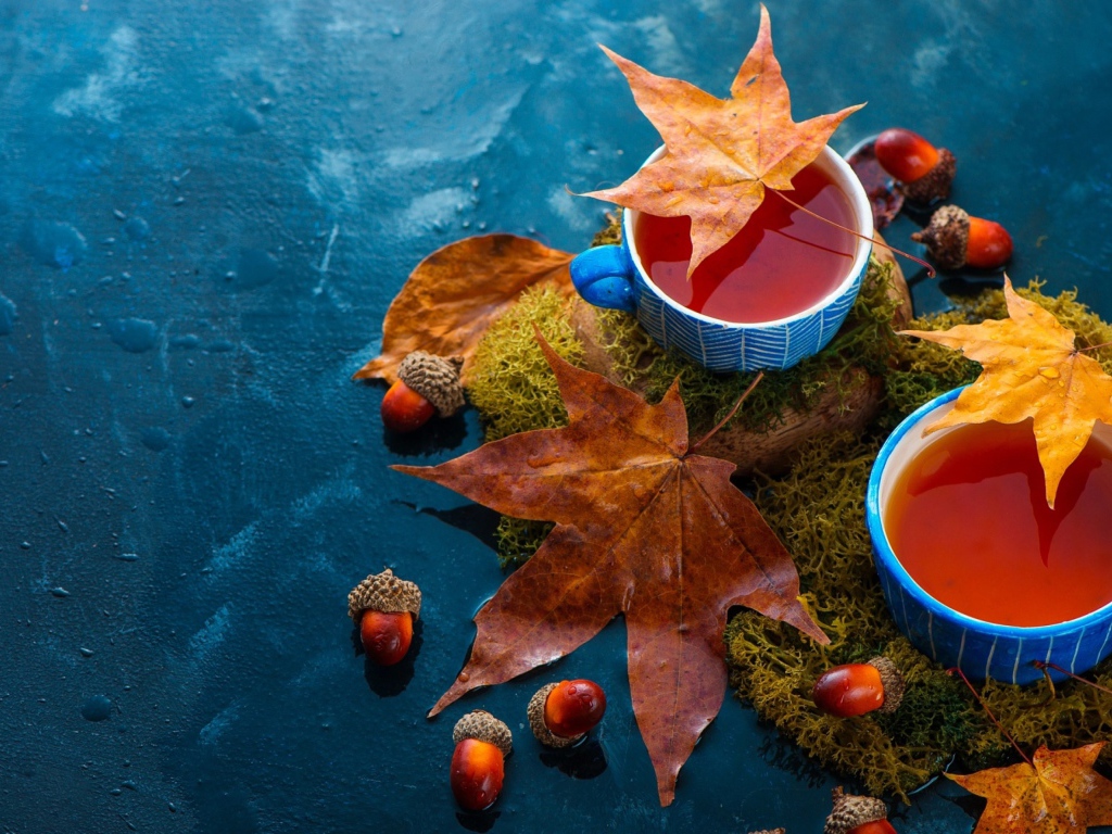 Чай на столе с осенними листьями и желудями 