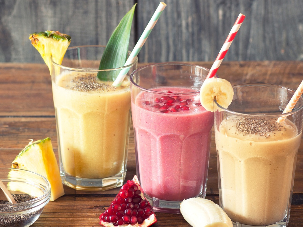 Три стакана смузи на столе с трубочками