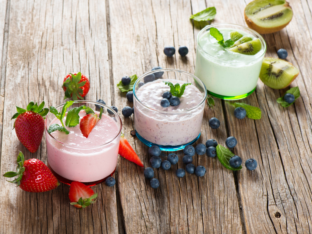 Три стакана смузи с ягодами на деревянном столе