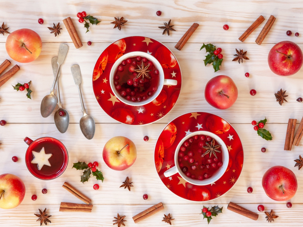Две чашки клюквенного чая на столе с корицей, яблоками и бадьяном
