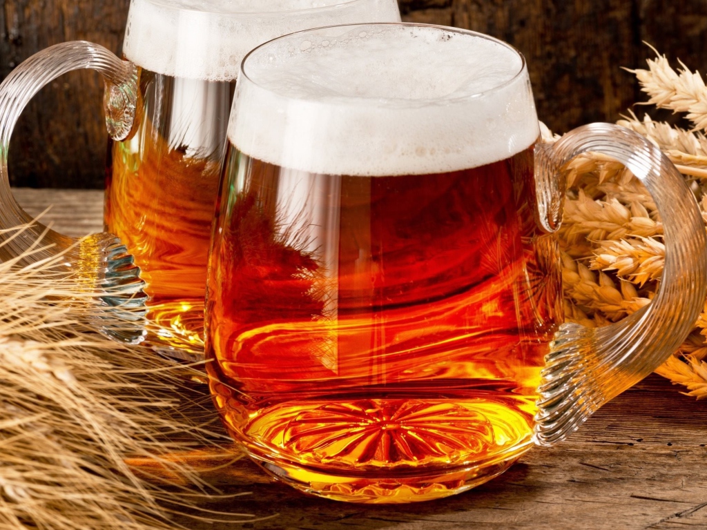 Два бокала пива на столе с колосьями пшеницы