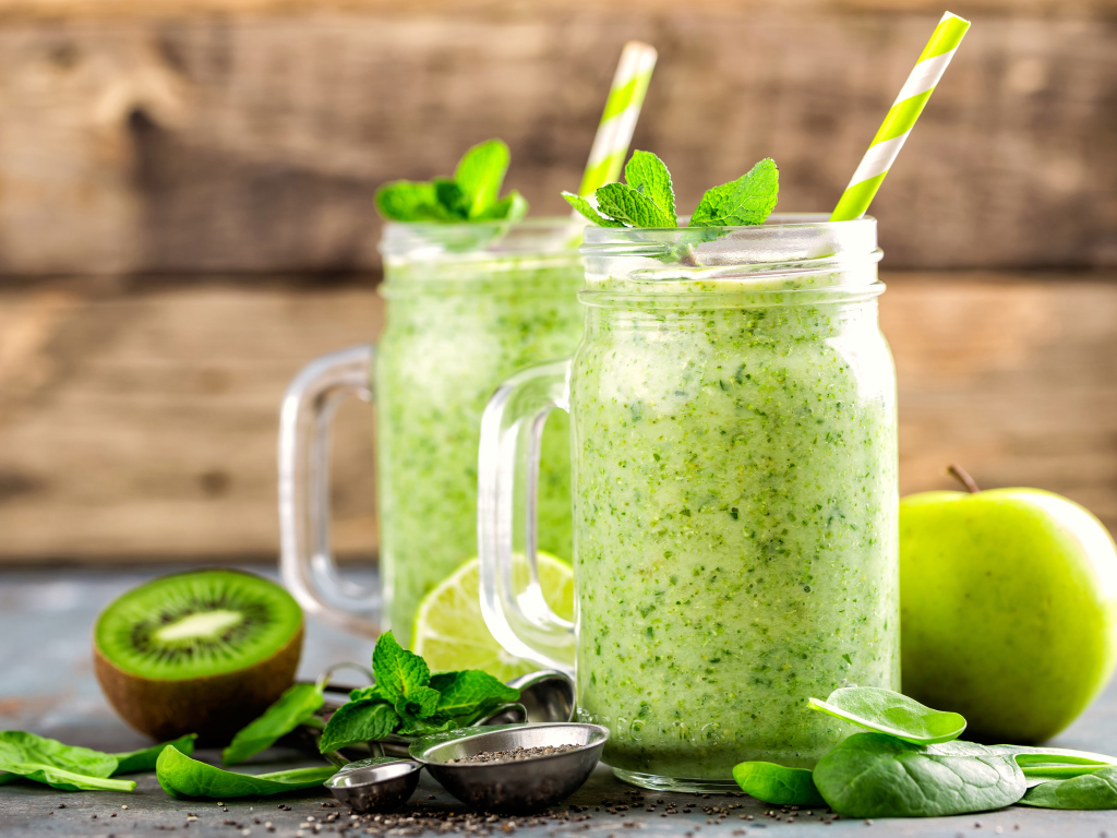 Два зеленых смузи на столе с киви, мятой и зеленым яблоком