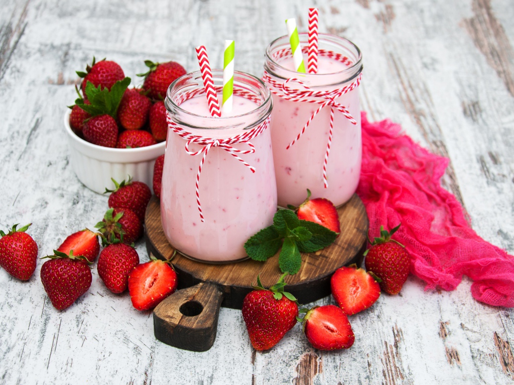 Две банки смузи стоят на доске на столе с клубникой