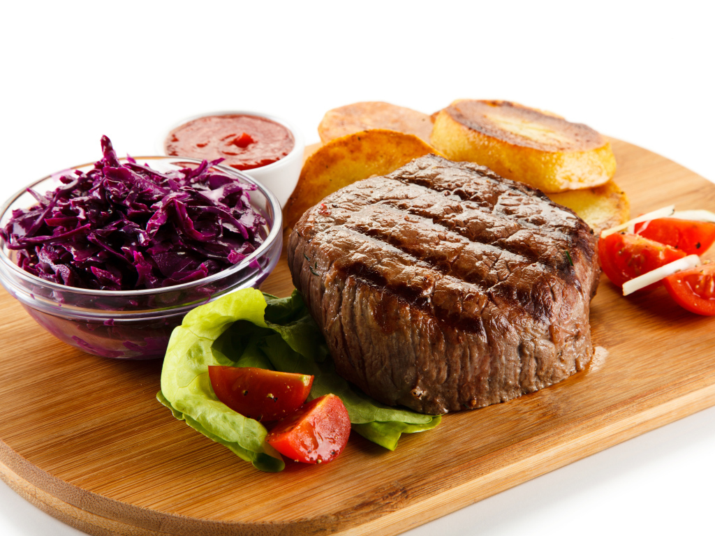 Кусок мяса гриль на доске с салатом и овощами