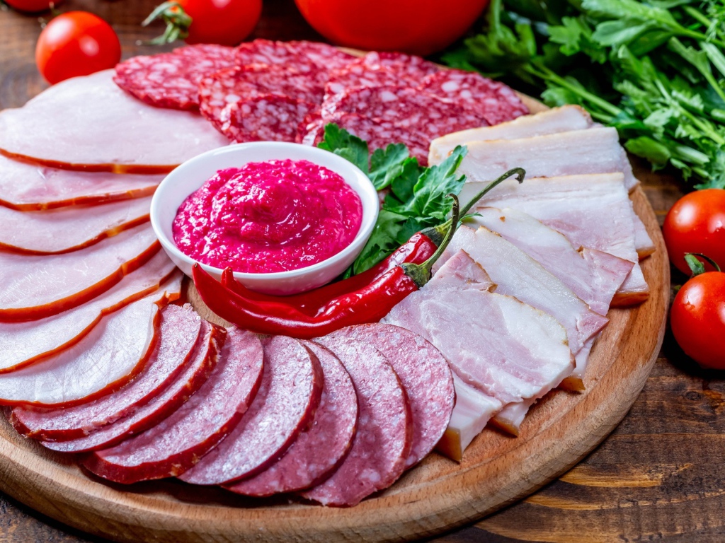 Мясная нарезка на доске с соусом, красным перцем,  помидорами и зеленью 