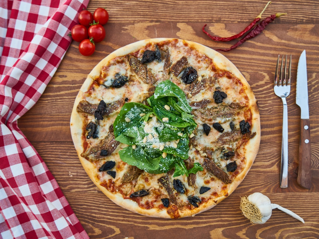 Пицца с мясом и шпинатом на столе 