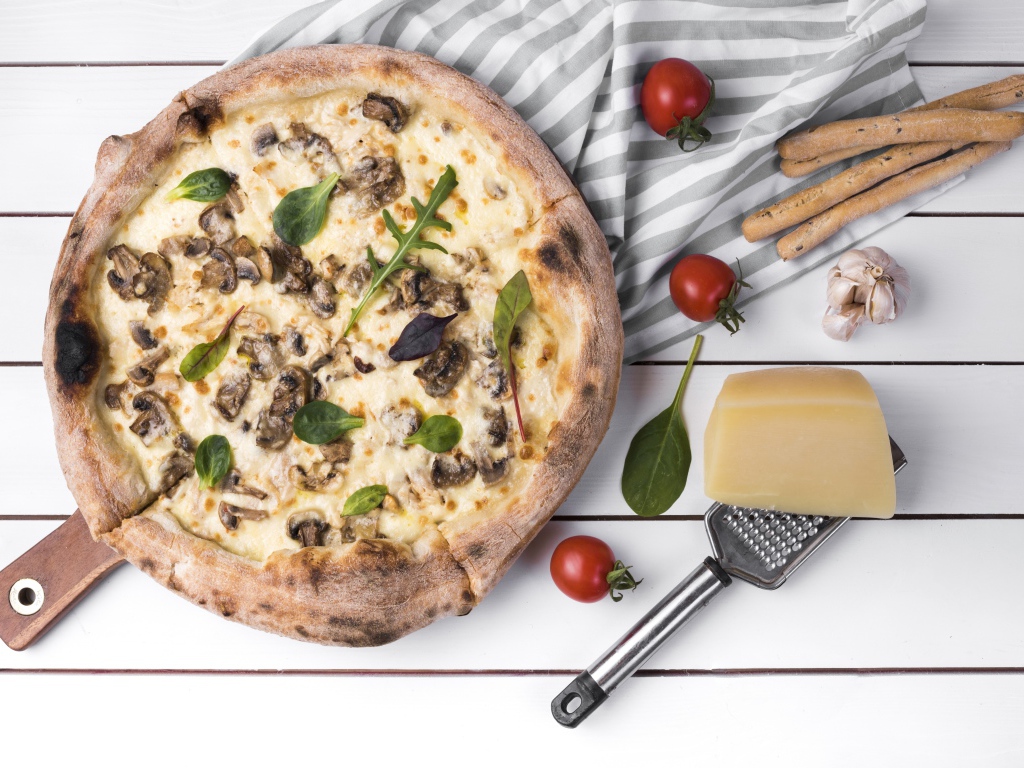 Пицца с грибами на столе с сыром и овощами