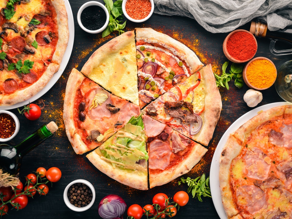 Пицца с различными начинками  на столе со специями