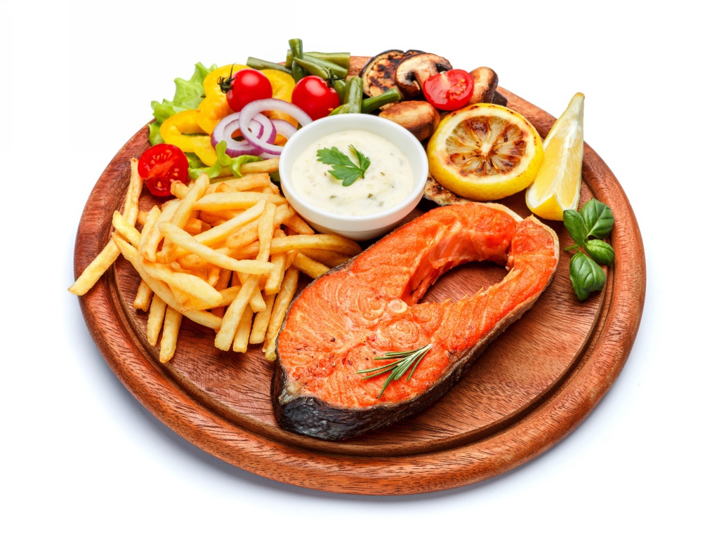 Рыба на доске с картофелем фри, овощами и соусом