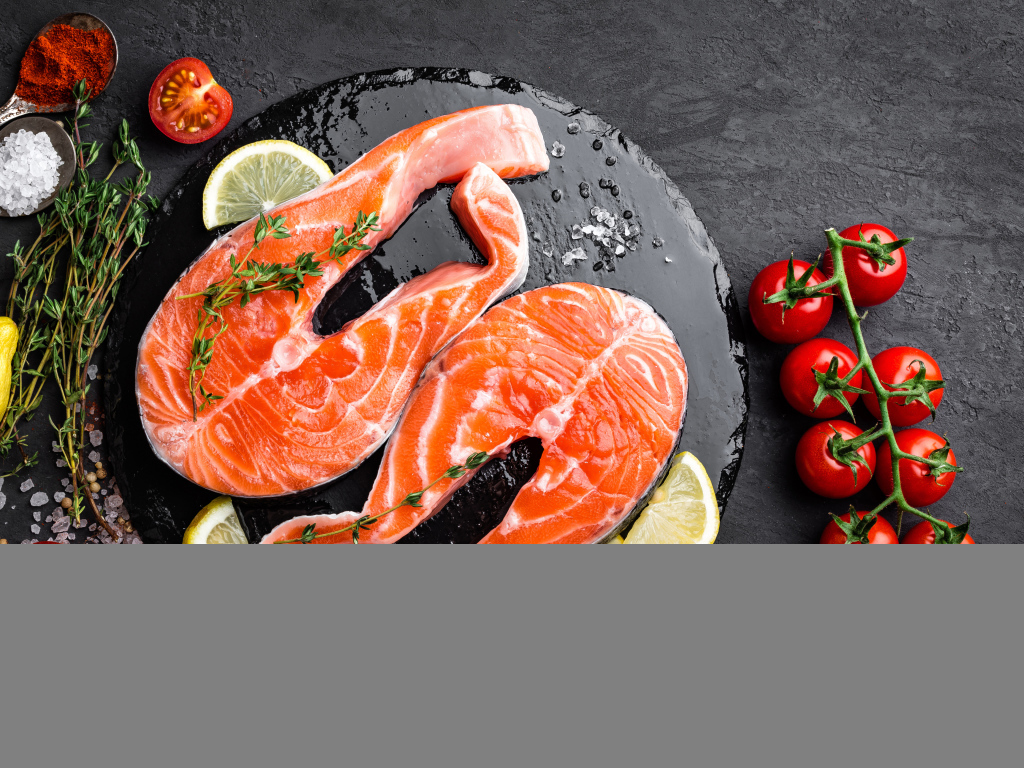 Два куска красной рыбы с овощами на черном фоне