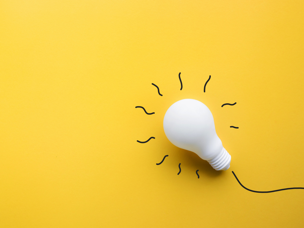 Белая лампочка лежит на желтой поверхности 