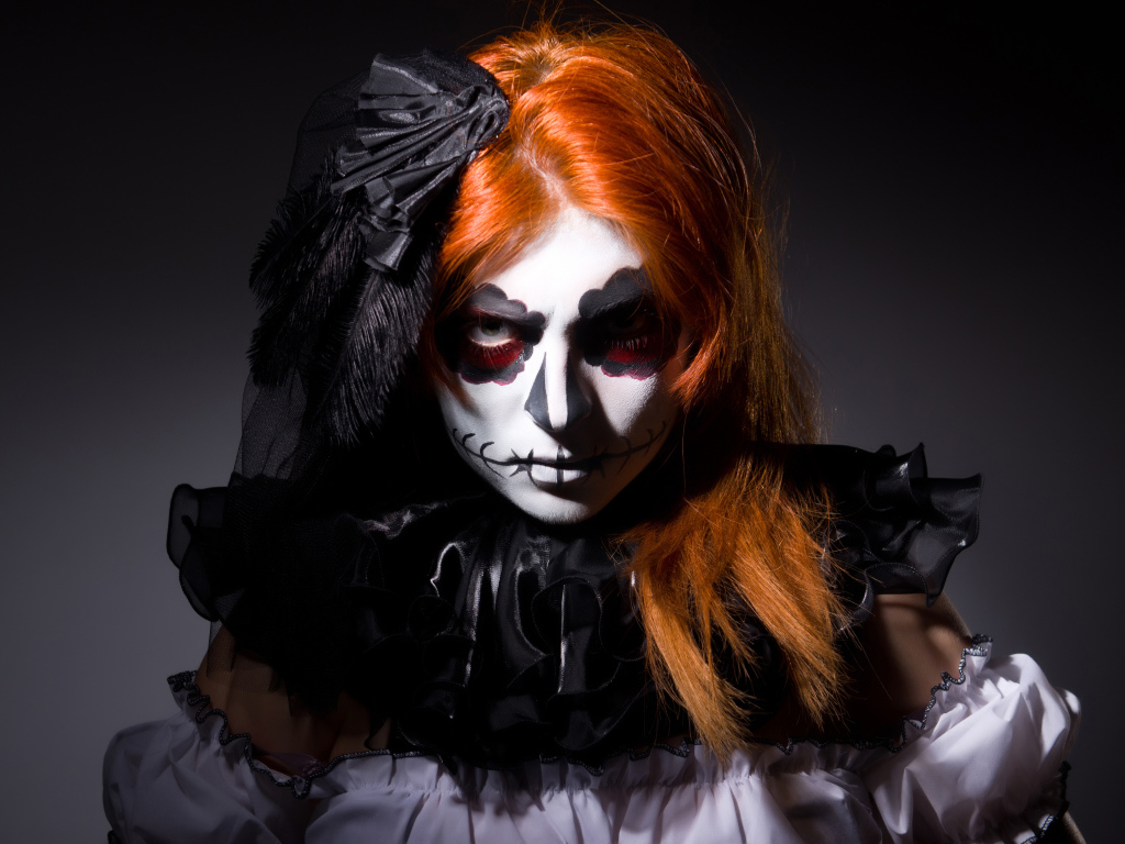 Рыжеволосая девушка с маской на лице на Хэллоуин 