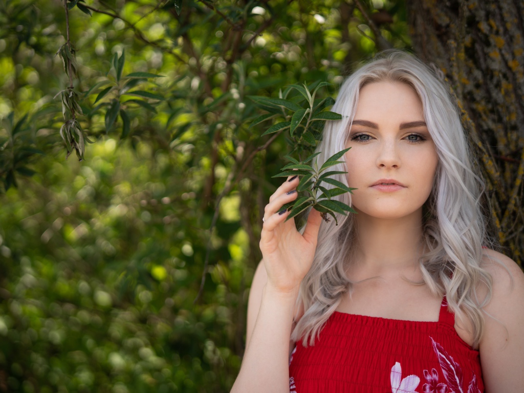 Красивая блондинка стоит у дерева 